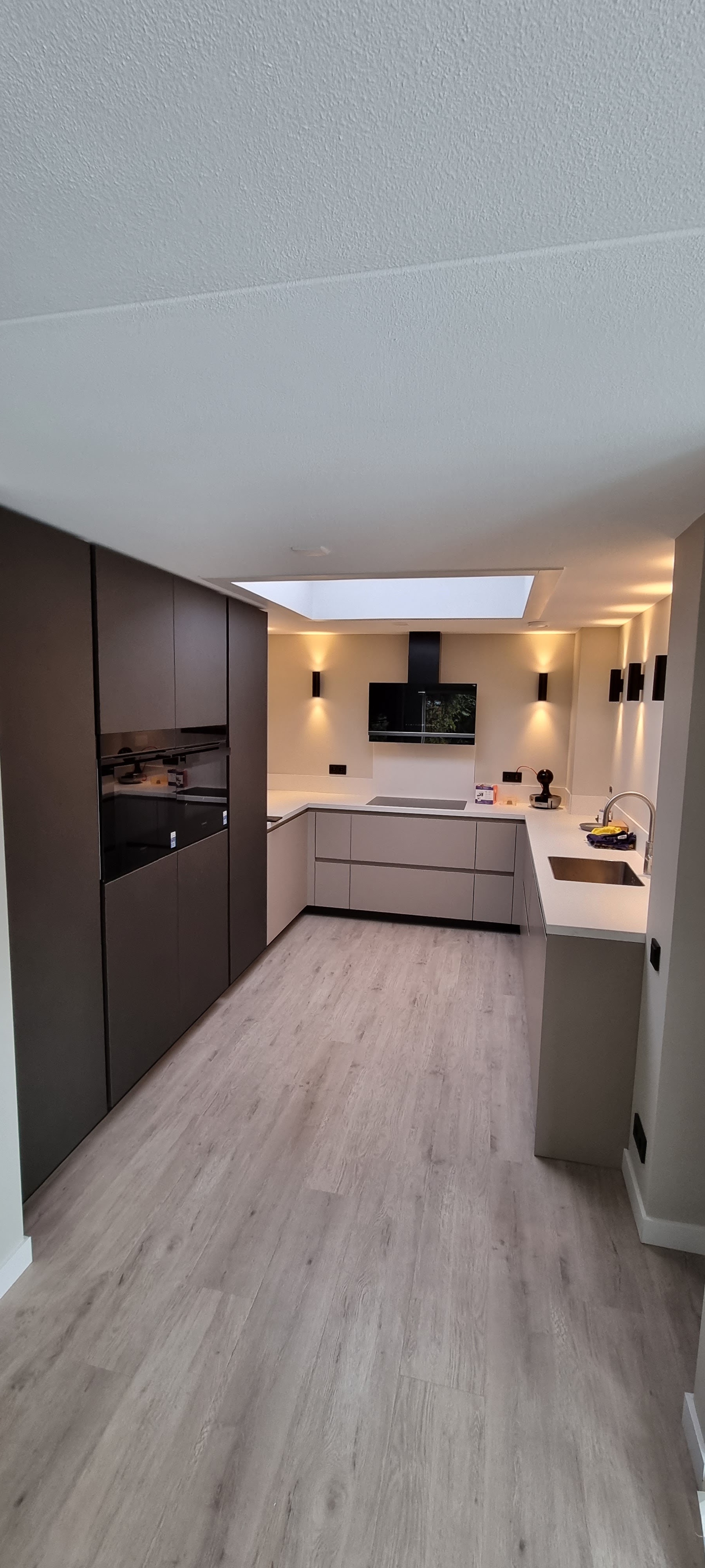 Lange keuken met antraciet hoge kasten, lichtkoepel en houten vloer